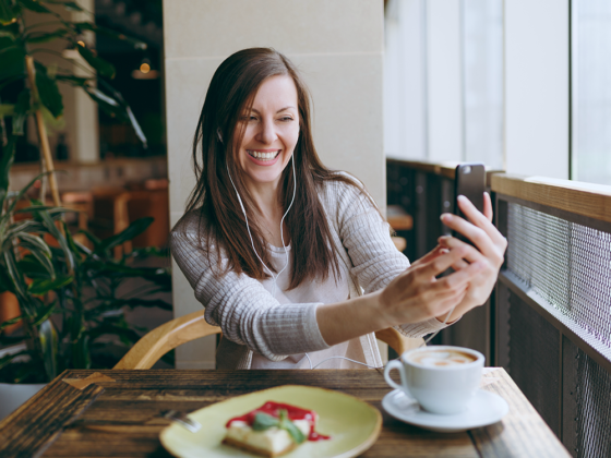 Building a cohesive team. Woman taking a selfie while eating a cheesecake and drinking coffee.