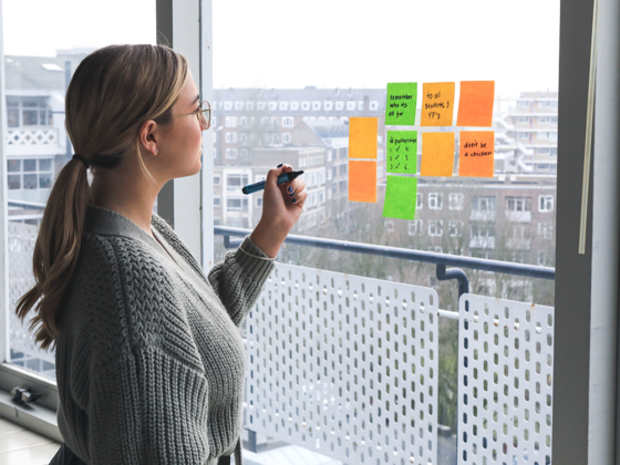 female writing her business culture plans down on sticky notes
