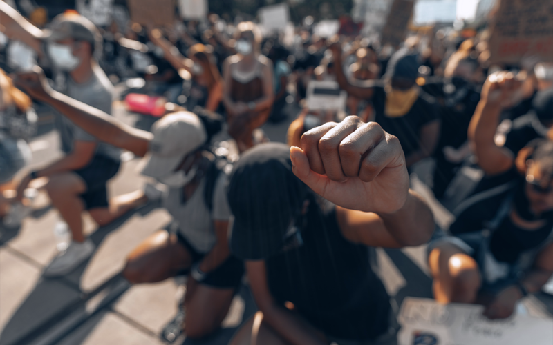 people standing with their fists high in a black lives matter march
