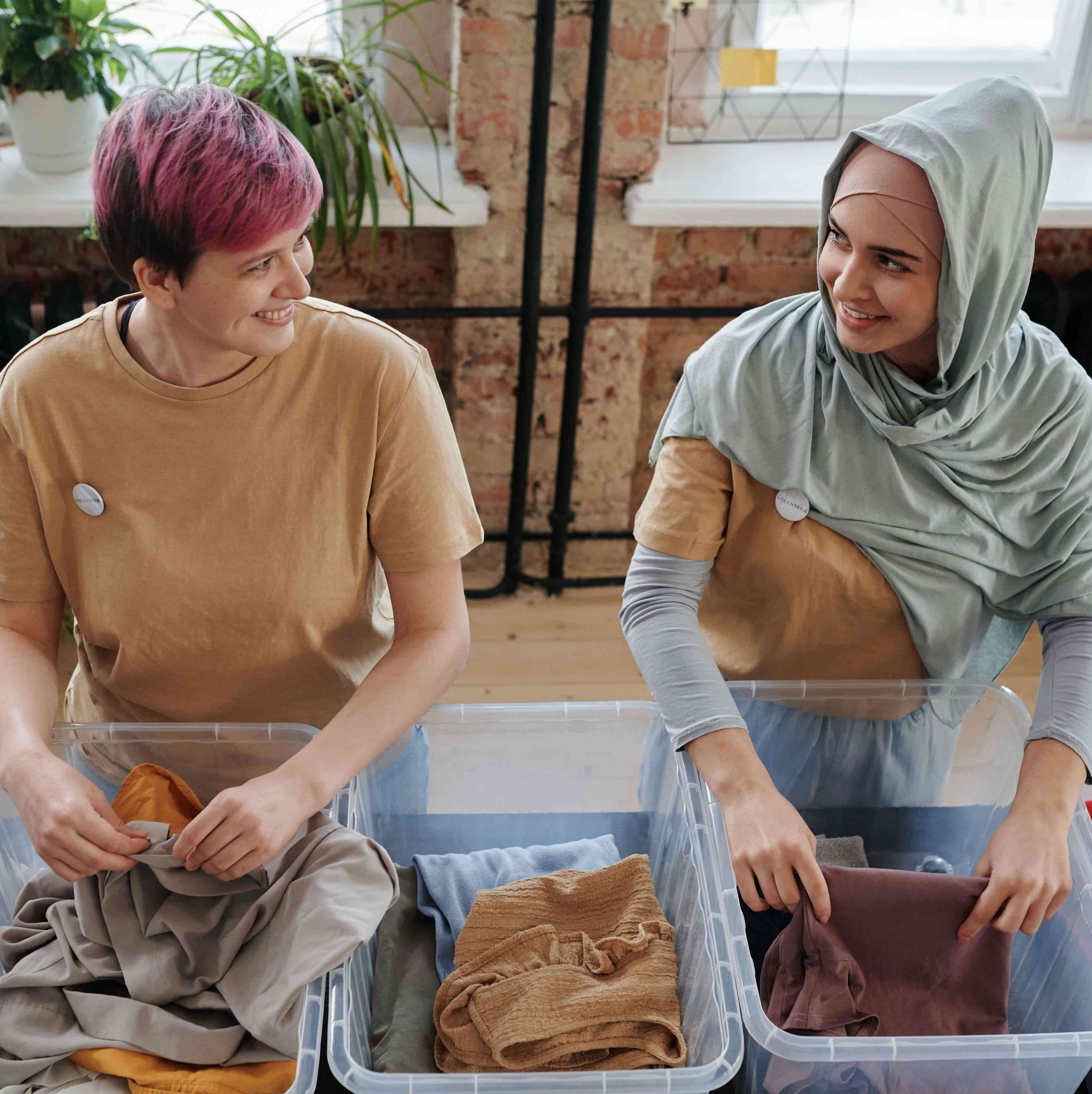 Two persons collecting clothes in plastic boxes for charity
