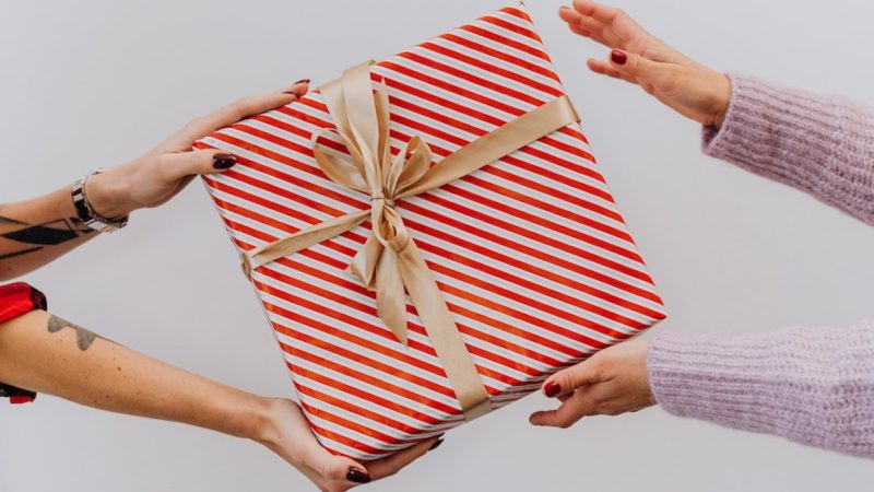 A person presenting a gift box to another person
