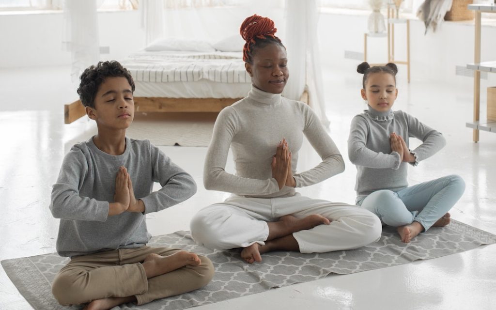 An adult person and 2 children meditating 