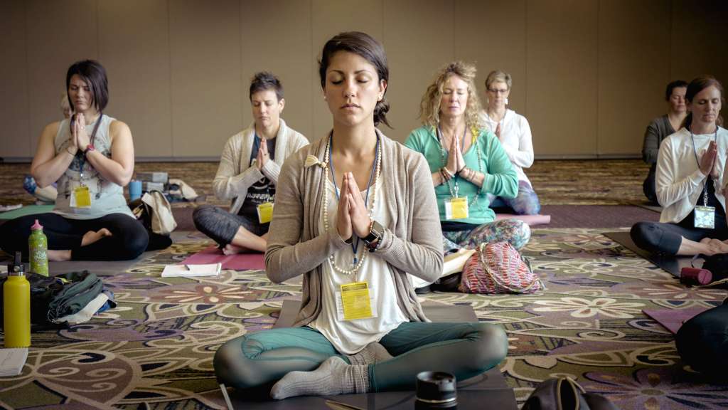 Employees sitting in lotus pose while taking part in the offsite mindfulness workshop
