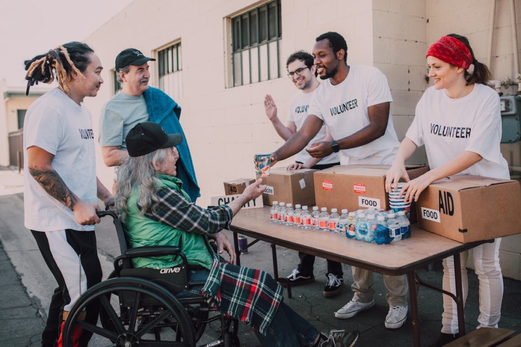 A team of employees during a company volunteer event handing out water to a person on a wheelchair