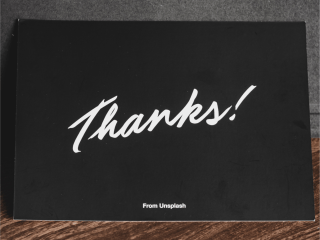 Black thank you card laid on a wooden table