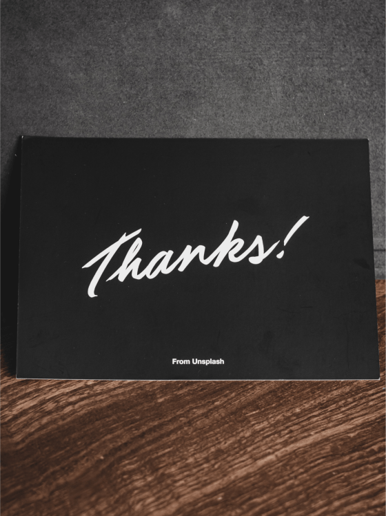 Black thank you card laid on a wooden table