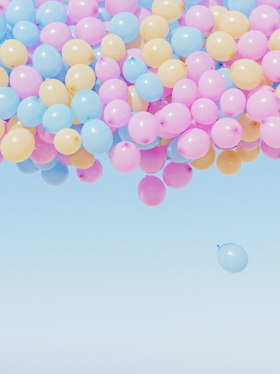 Pink, yellow, and blue balloons floating in the sky.